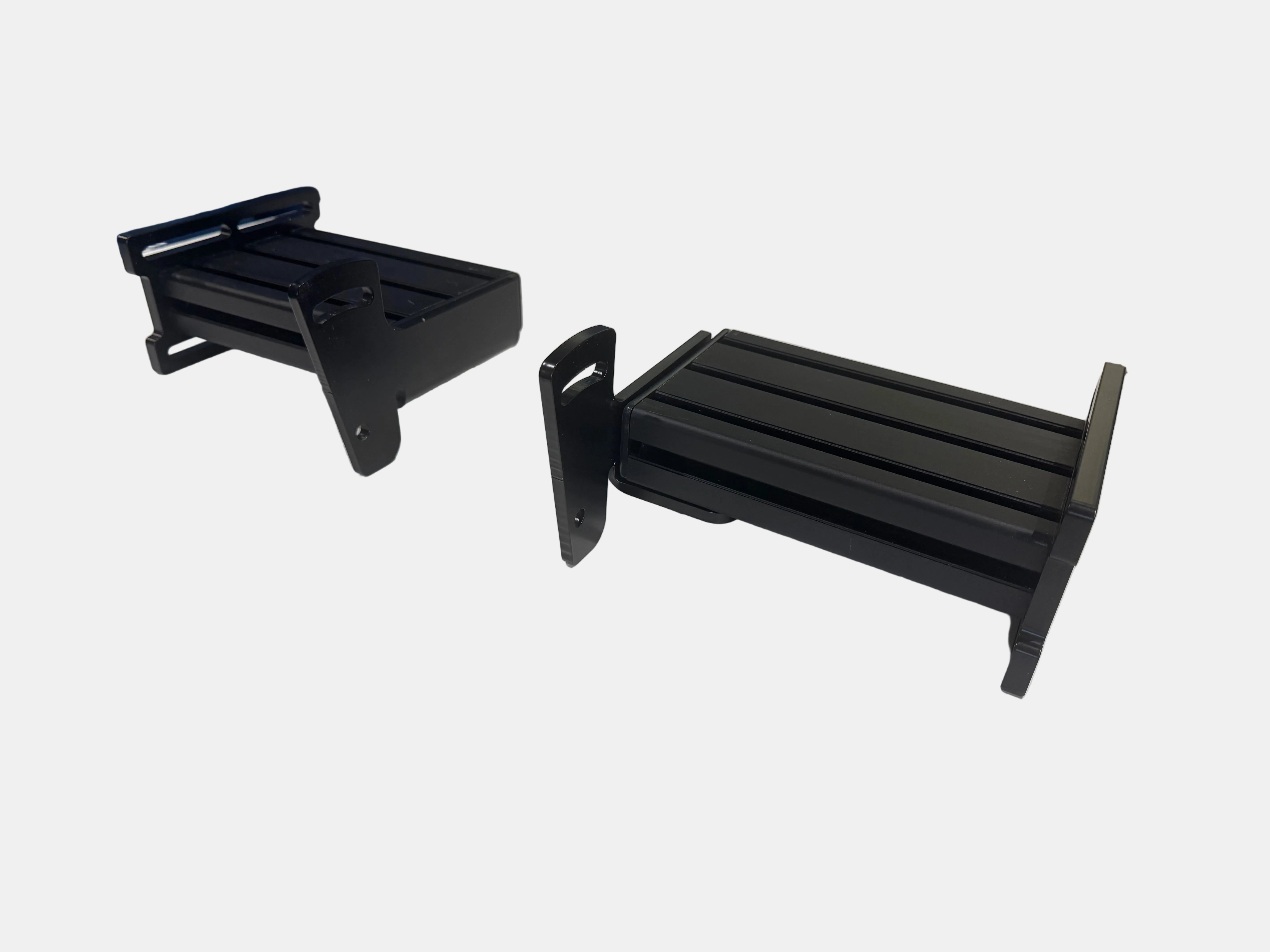 Black metal brackets on a workshop table with tools and equipment in the background