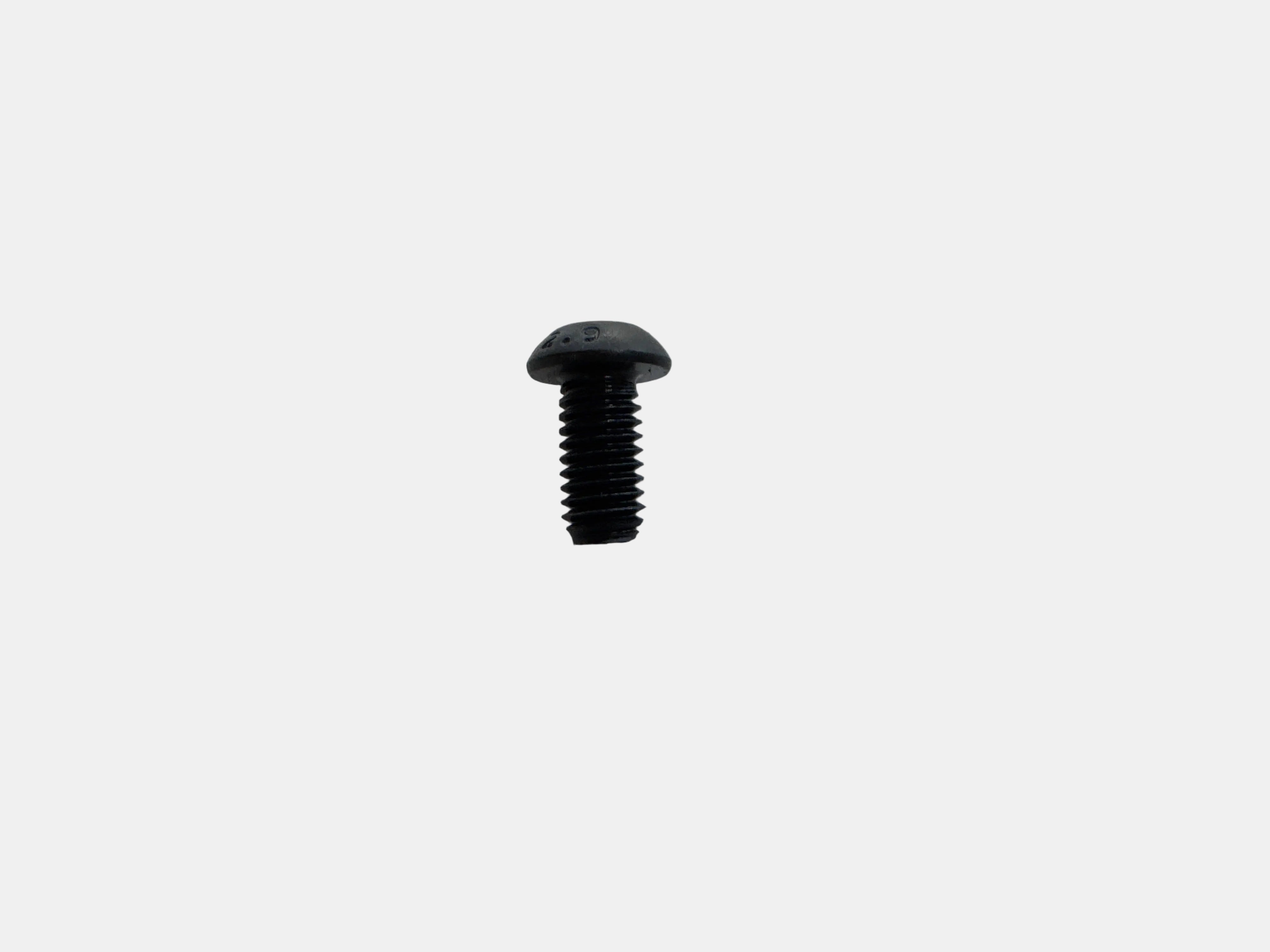 A single small black metal screw with a rounded flat head and threaded shaft, placed on a plain light gray surface.